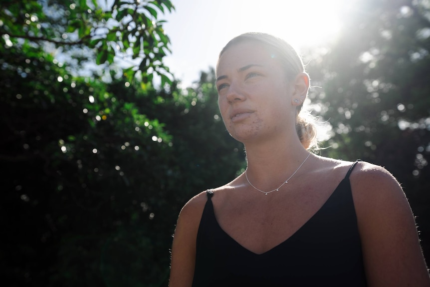 Image looks up at a young woman looking out into the distance