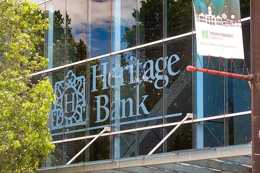 A close up of a glass-fronted building with Heritage Bank and its logo written on it.