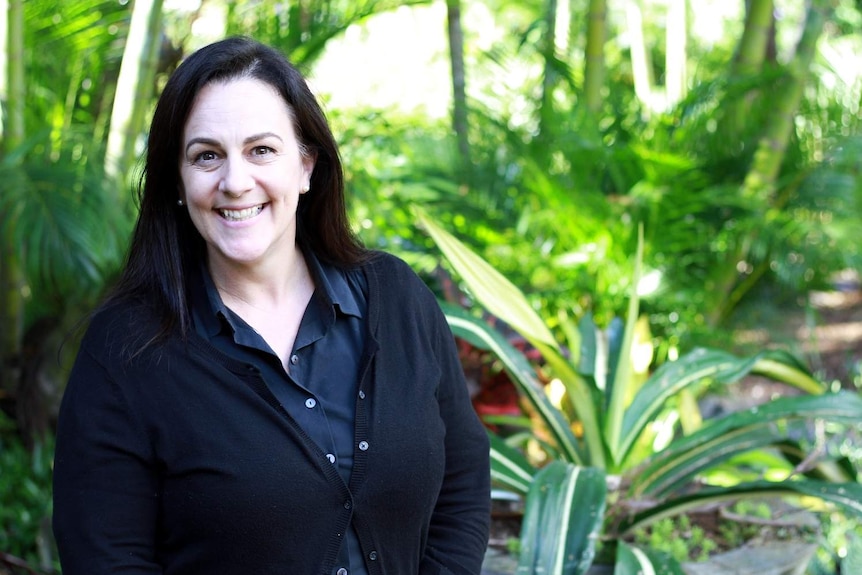 New Zealand citizen Lisa Kibblewhite smiles in front of nice greenery.