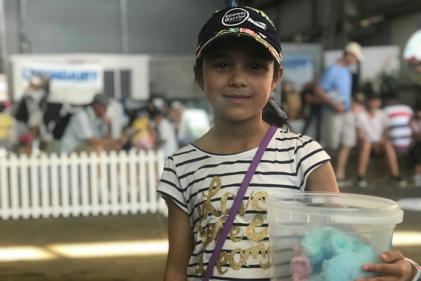 A girl holds a tub of fairy floss