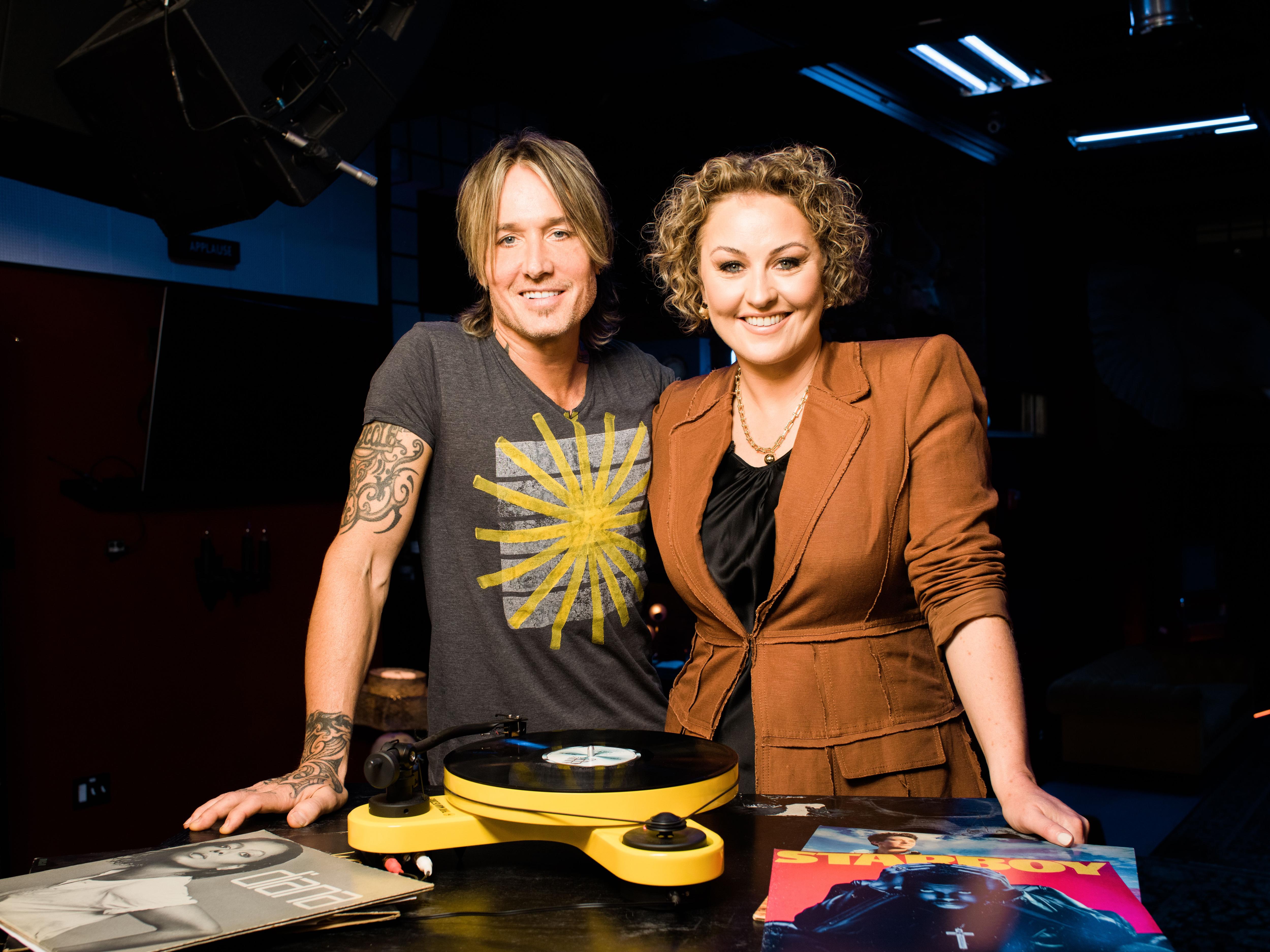 Urban and Rowe standing next to a record player looking to camera.