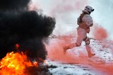 A Russian soldier skips past red smoke from a flare as a fire rages in the foreground