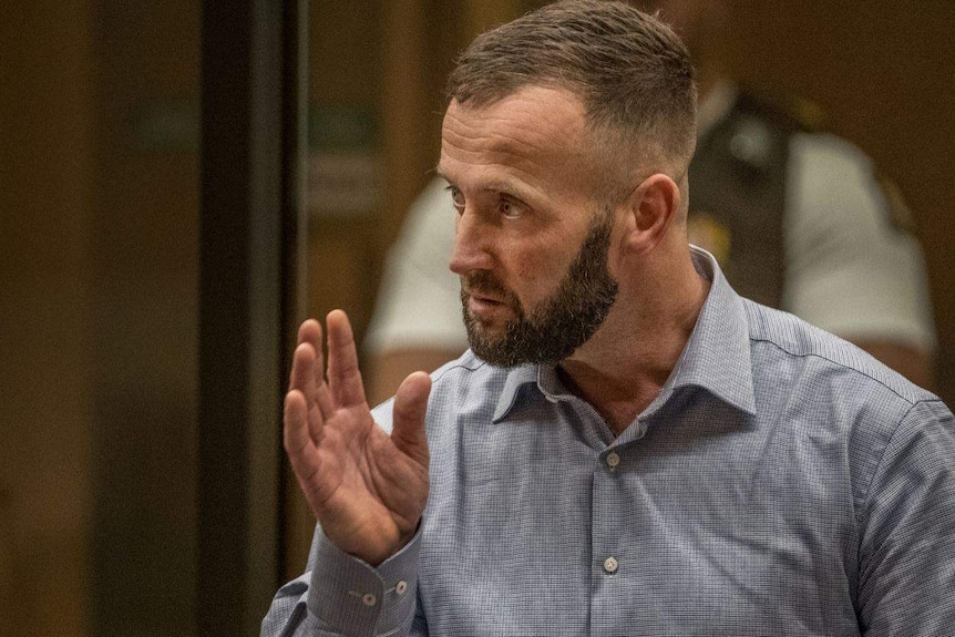 A man in a shirt gestures while speaking in a court room