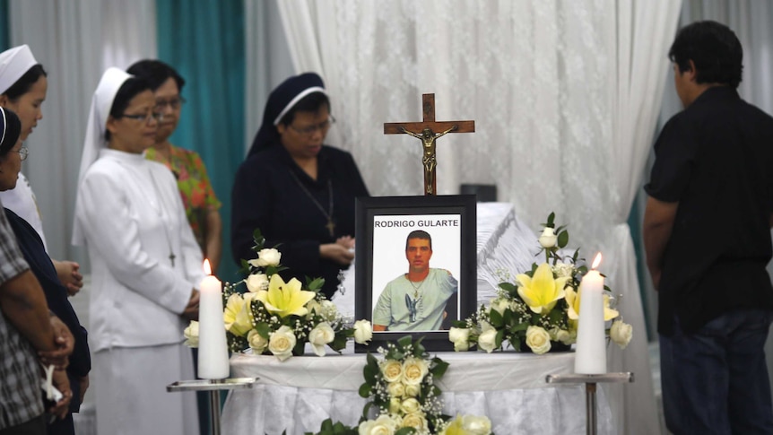 Catholic nuns pray beside the coffin of Rodrigo Gularte at a funeral home in Jakarta.