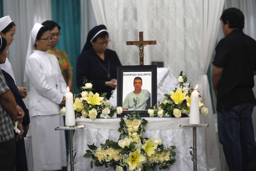 Catholic nuns pray beside the coffin of Rodrigo Gularte at a funeral home in Jakarta.