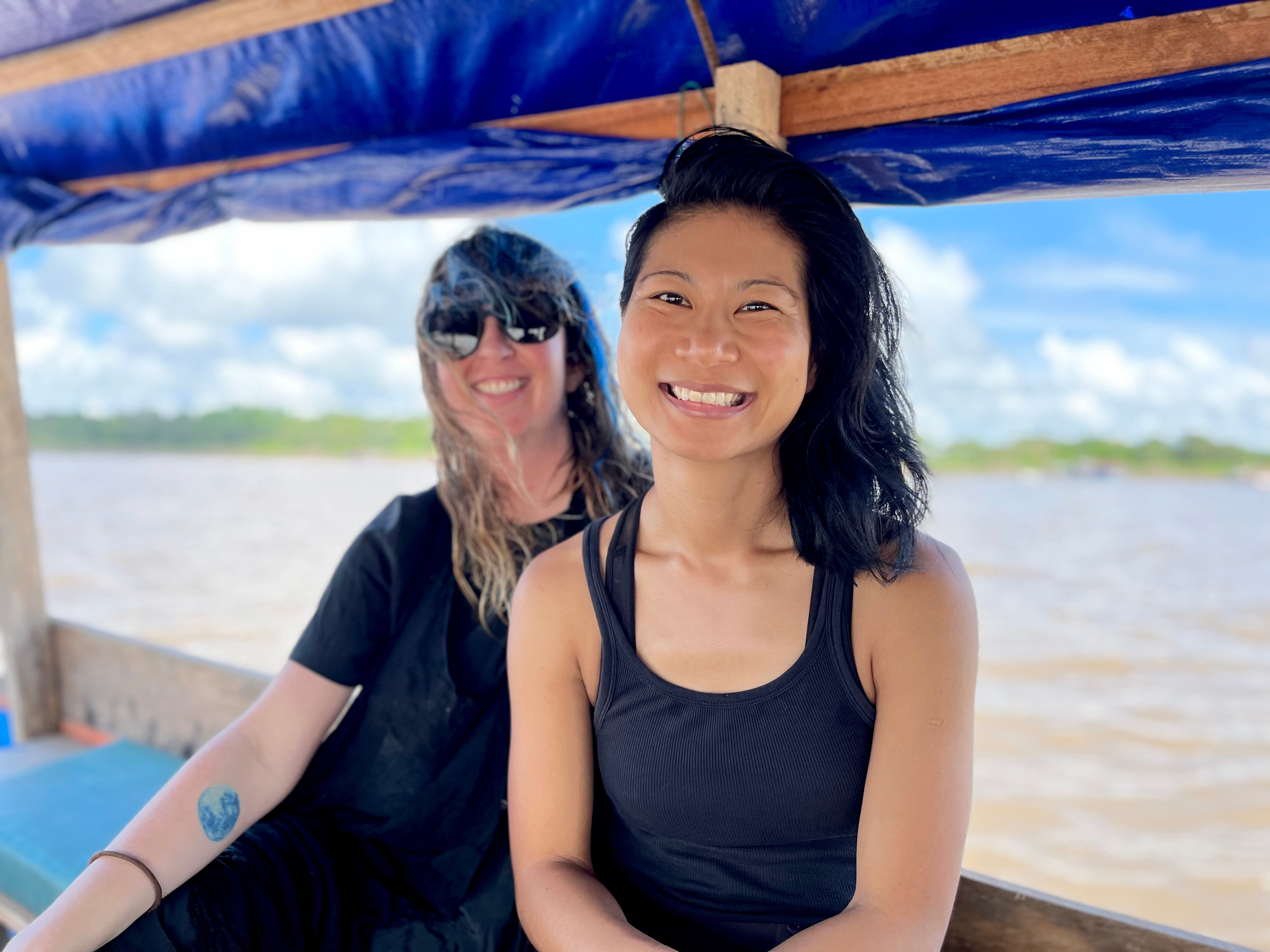A smiling Inga and friend sit on a boat as they float down Colombia's Amazon River