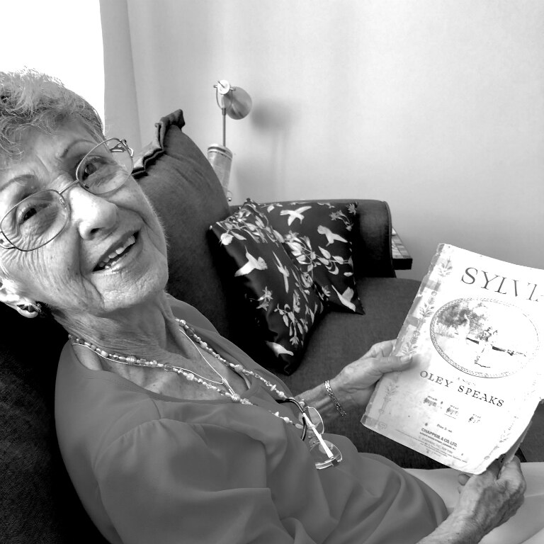 Woman sitting on the couch holding a piece of classical music.