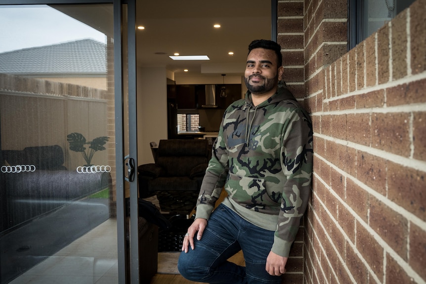 a man with a beard stands in the doorway of his house.