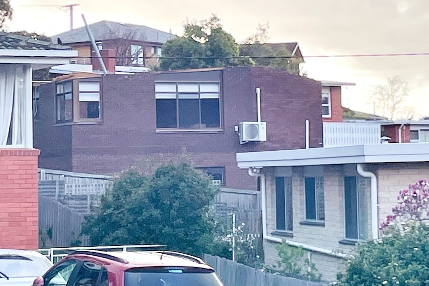 A brick house with no roof among other houses on a hill
