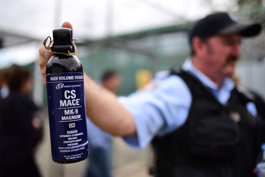 Prison officer holding a can of mace spray