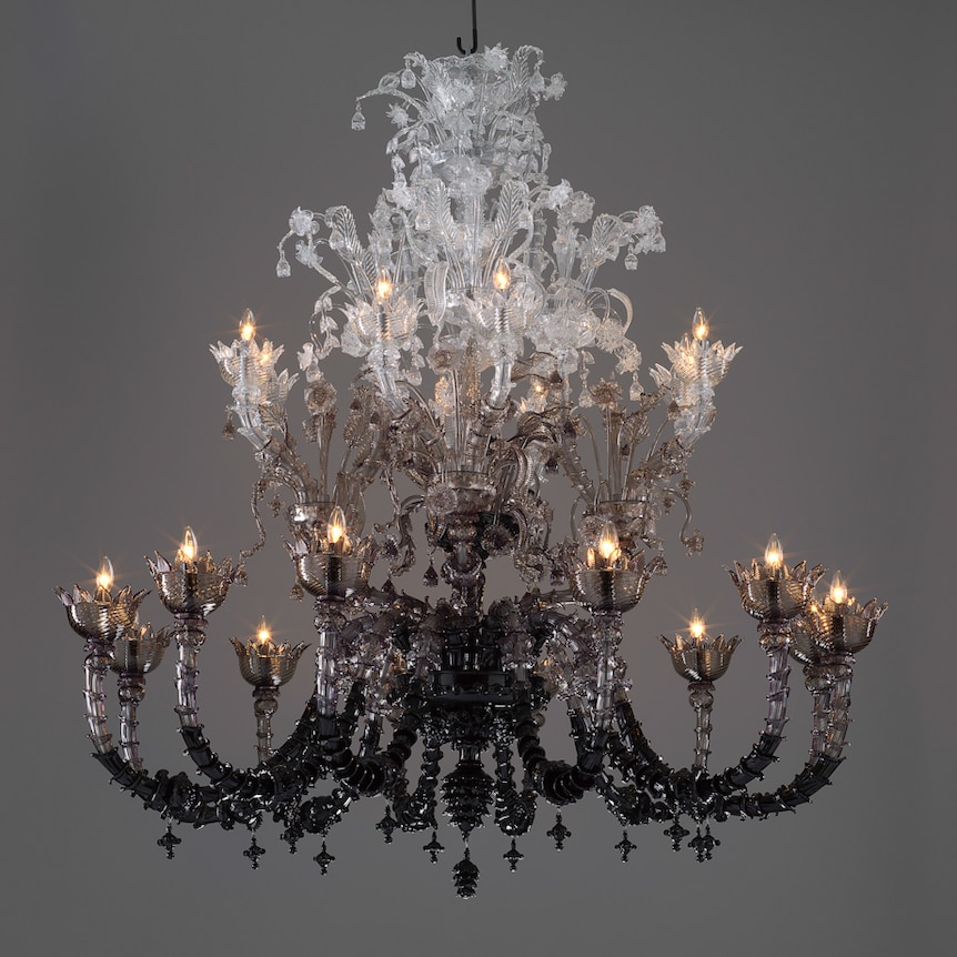 A baroque style chandelier made from glass, with a colour gradient running from dark at bottom to clear at top.