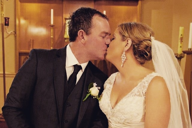 A bride and groom kiss on their wedding day.