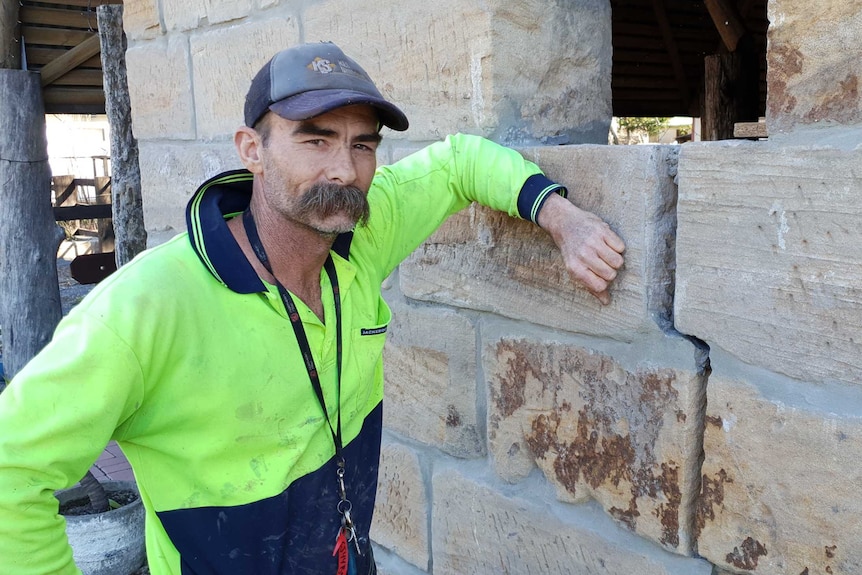 Justin Curran leans on a stone wall