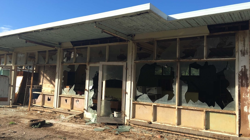 The outside of a house which has every window smashed and walls with holes punched through