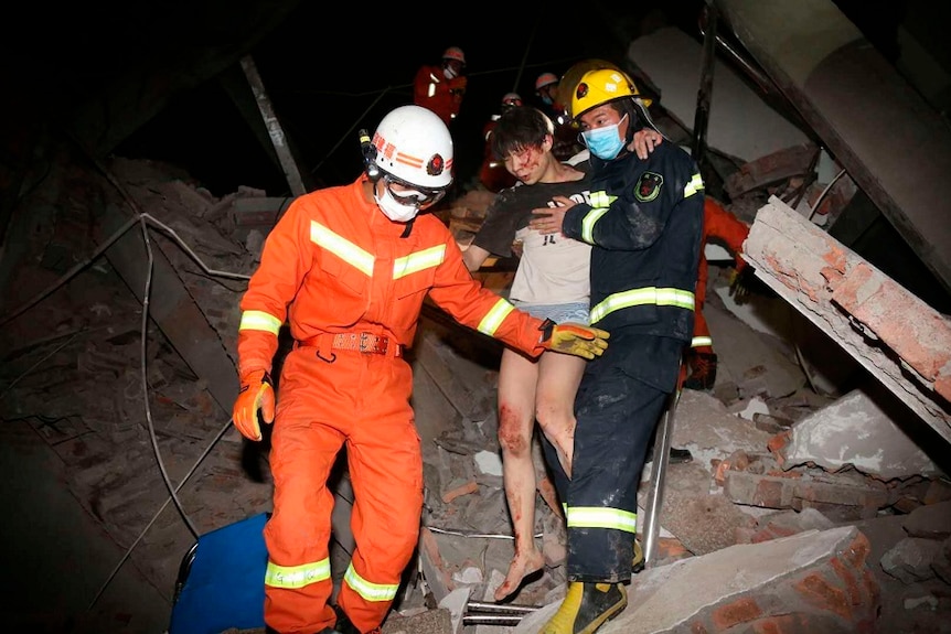 Rescue workers help a woman out of rubble.