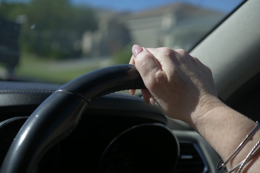 A woman's hand on a steering wheel