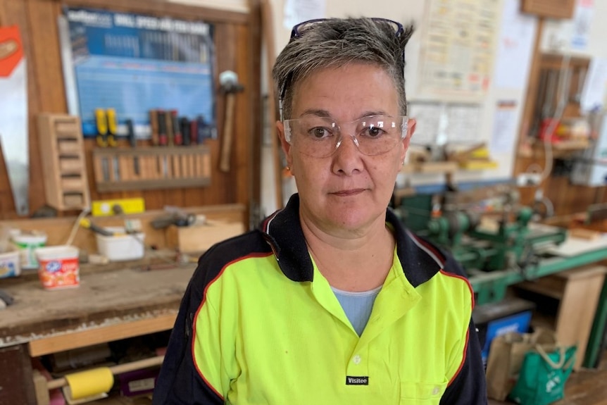 A woman wears safety glasses in a workshop