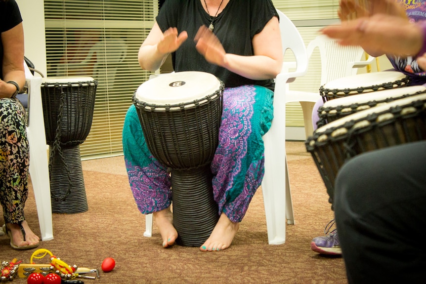 Drummer wraps feet around djembe drum