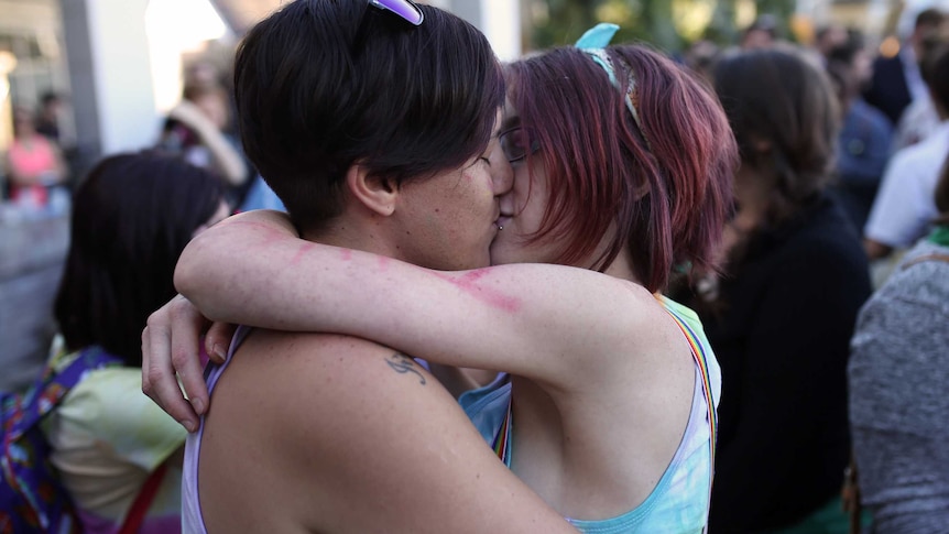 Perth couple Kayla Thompson and Jade Rous hug and kiss one another.