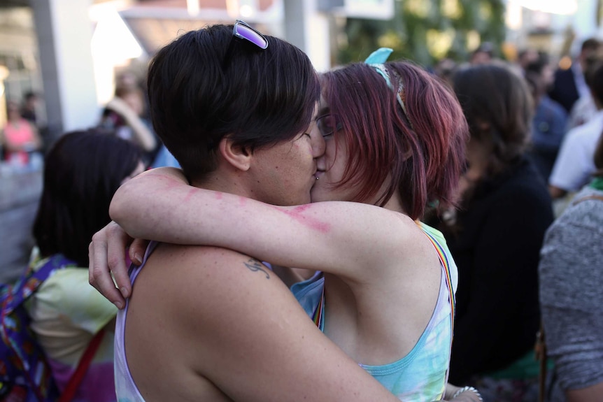 Perth couple Kayla Thompson and Jade Rous hug and kiss one another.