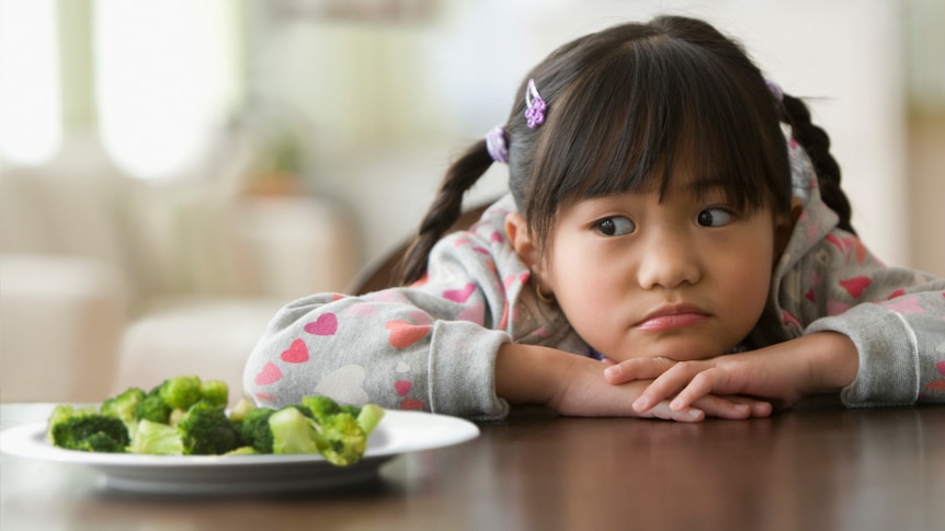 plate of broccoli and cauliflower in front of small girl