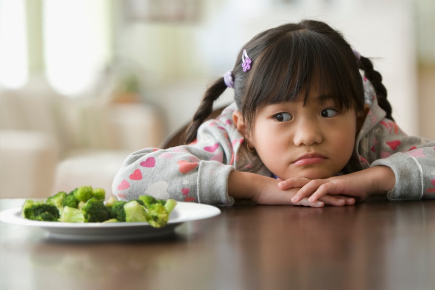 plate of broccoli and cauliflower in front of small girl