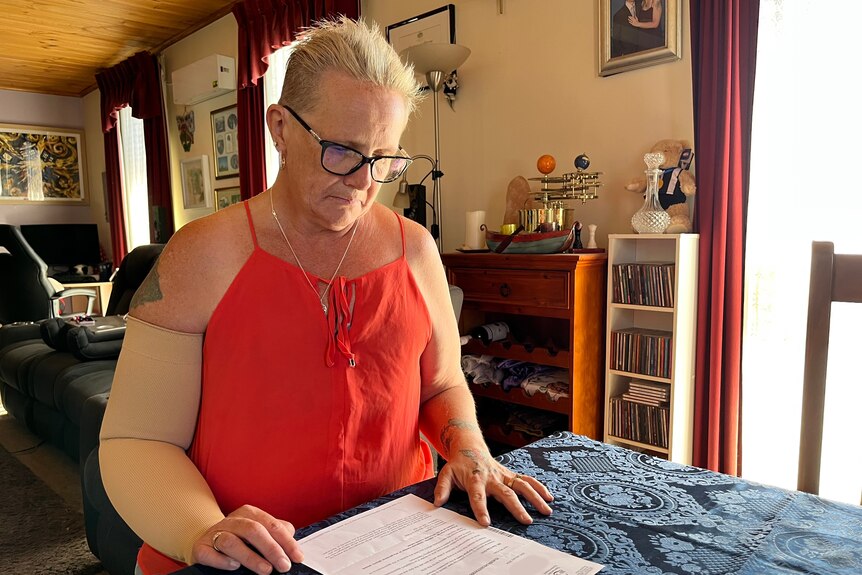 Sue Kole sits at a dining table with a printed letter from the Tasmania Health Service in front of her