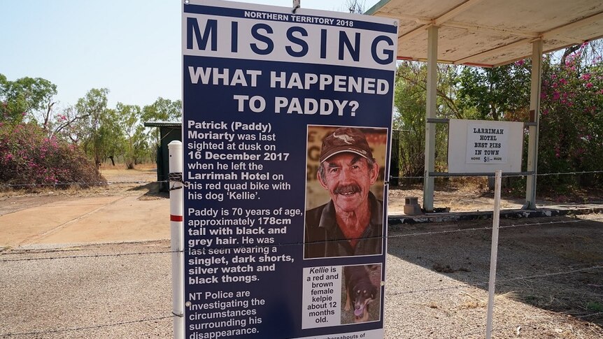 A poster with an image and details of a missing man is tied to a fencepost.