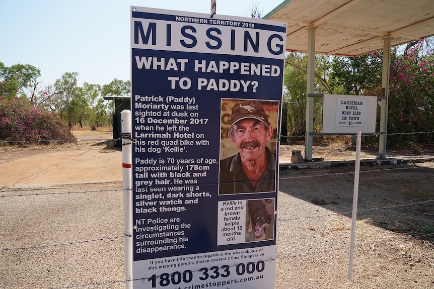A poster with an image and details of a missing man is tied to a fencepost.
