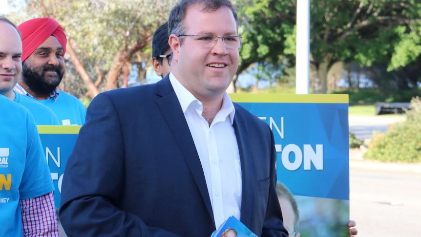 Liberal Party candidate for Tangney Ben Morton stands in front of supporters with placards.