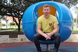 Wilson Tucker sitting in a blue chair in Perth's Hyde Park.