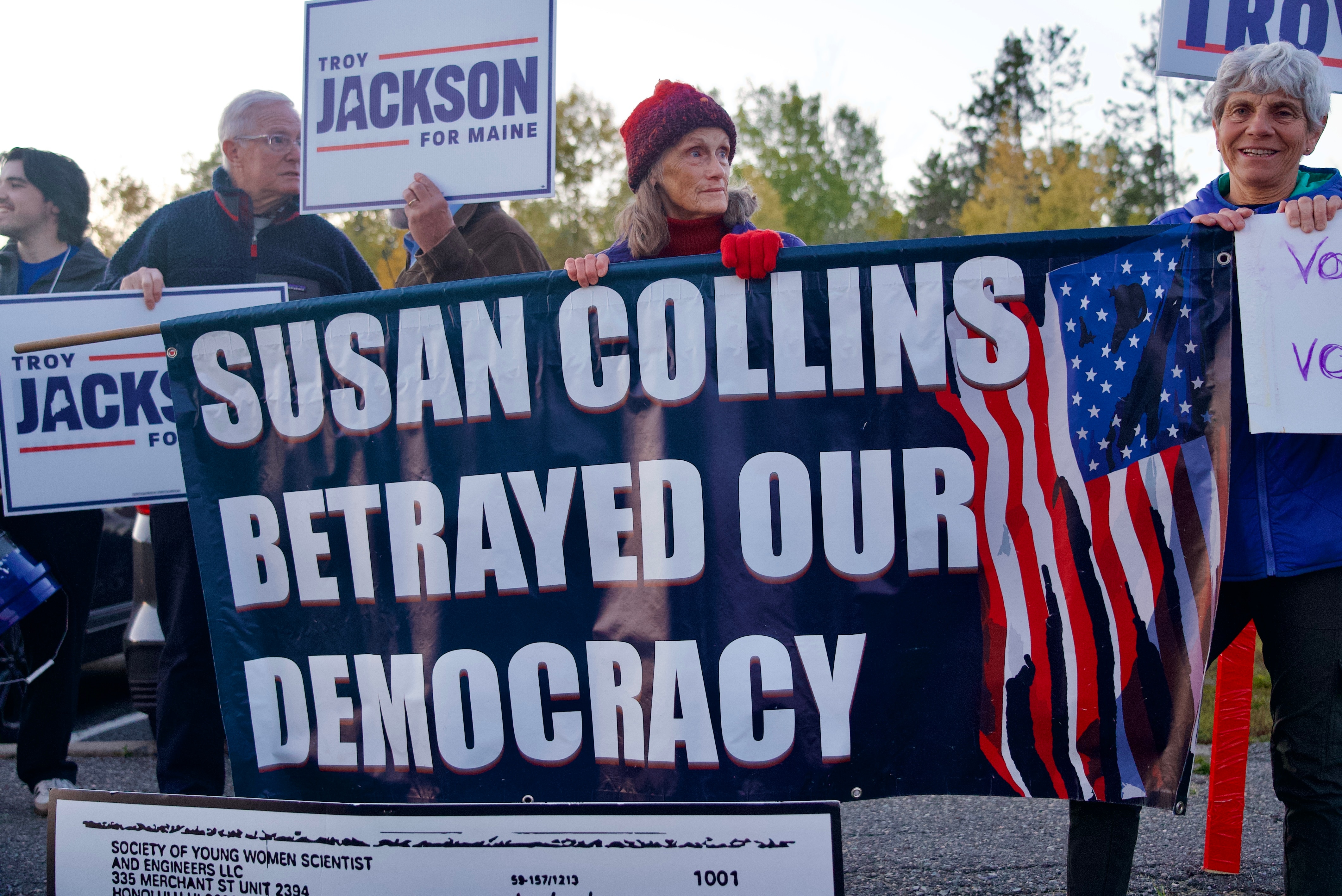 Mary Ann Larson holds a sign that says: "Susan Collins betrayed our democracy."