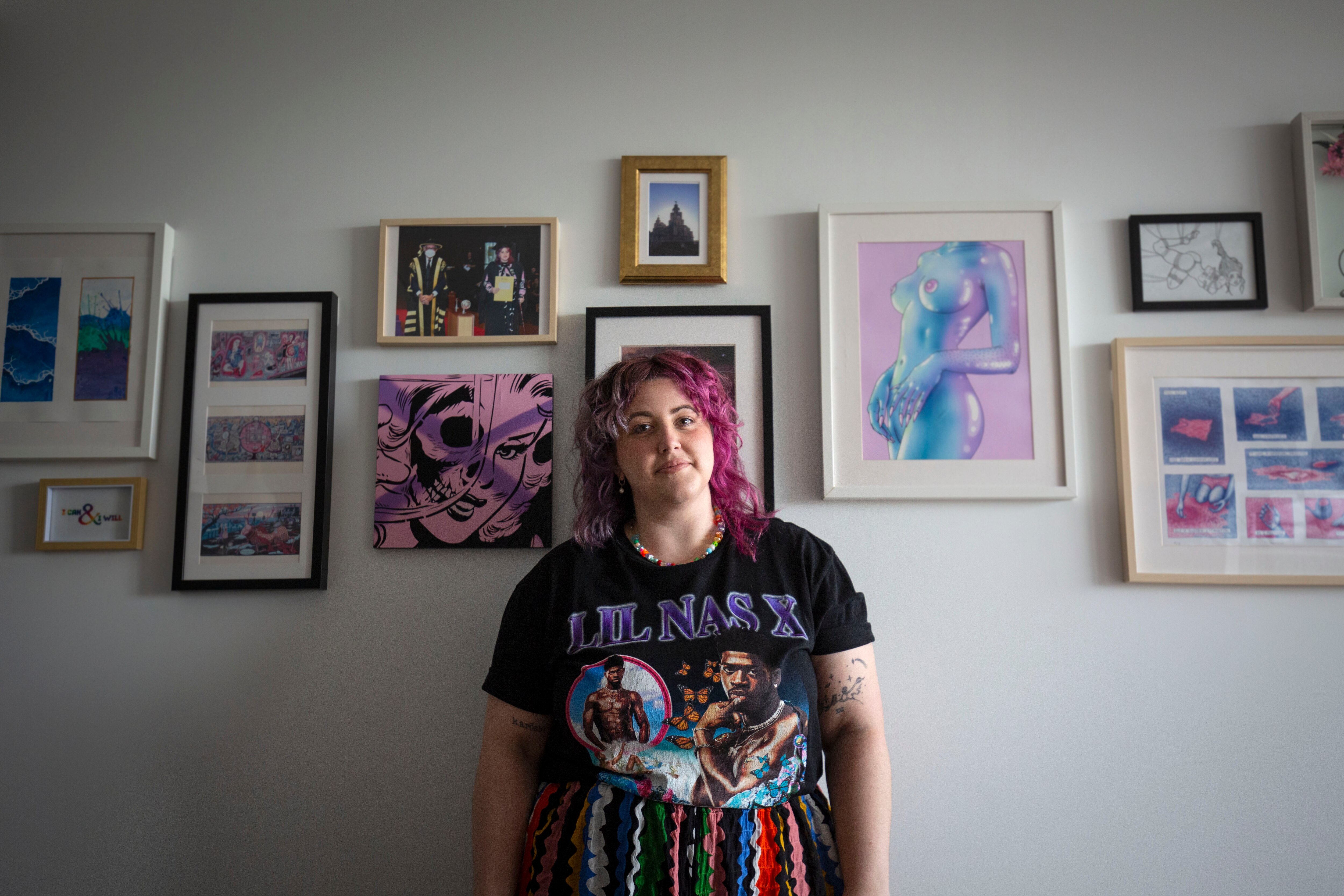 A person with pink hair and a colourful skirt in their apartment on a cloudy day