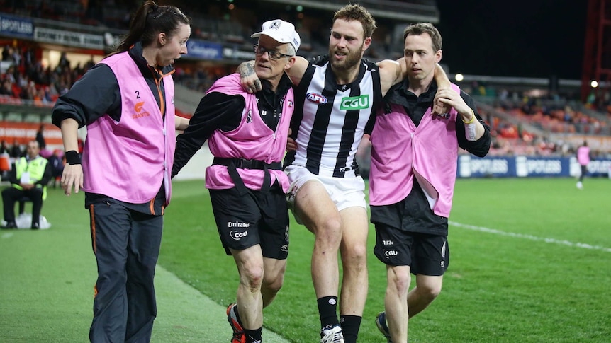 Collingwood's Brent Macaffer is assisted from the ground with a knee injury against GWS.