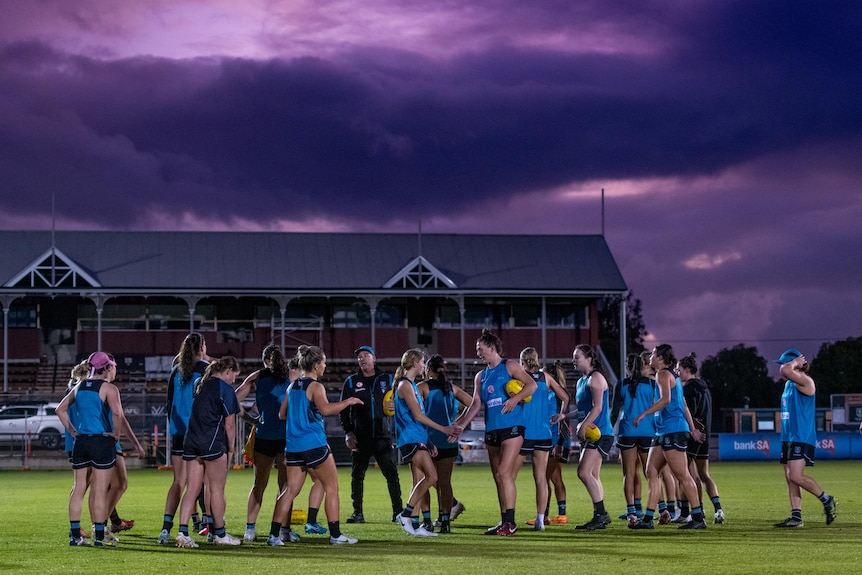 A group of Port Adelaide women's team in blue sportswear on field