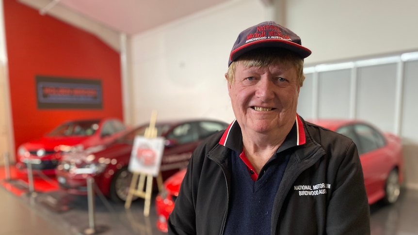 a man in a black and red outfit and hat smiles at the camera