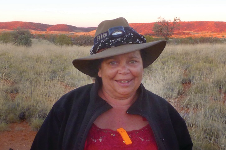 A woman in front of red Pilbara hills and grasses.