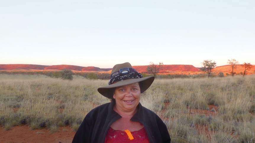 A woman in front of the hills and the red grasses of Pilbara.