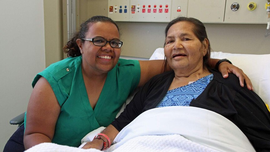 An elderly woman in a hospital bed with a younger woman.