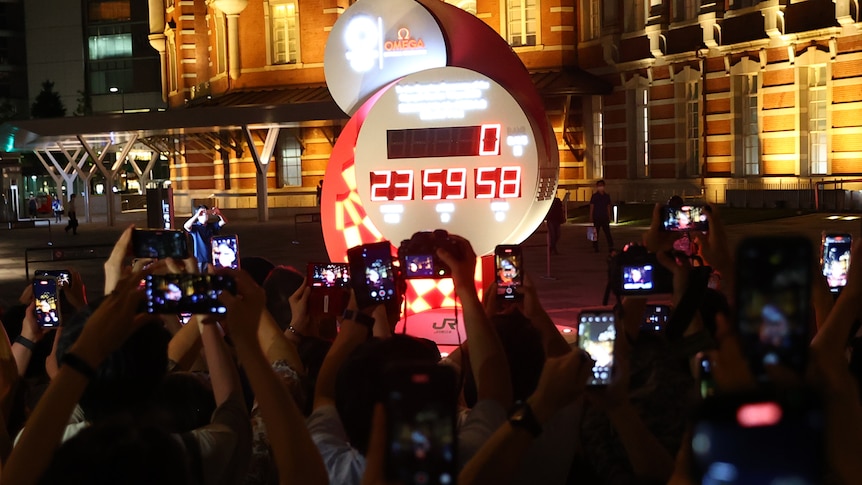 Dozens of people take photos of an oversized digital clock