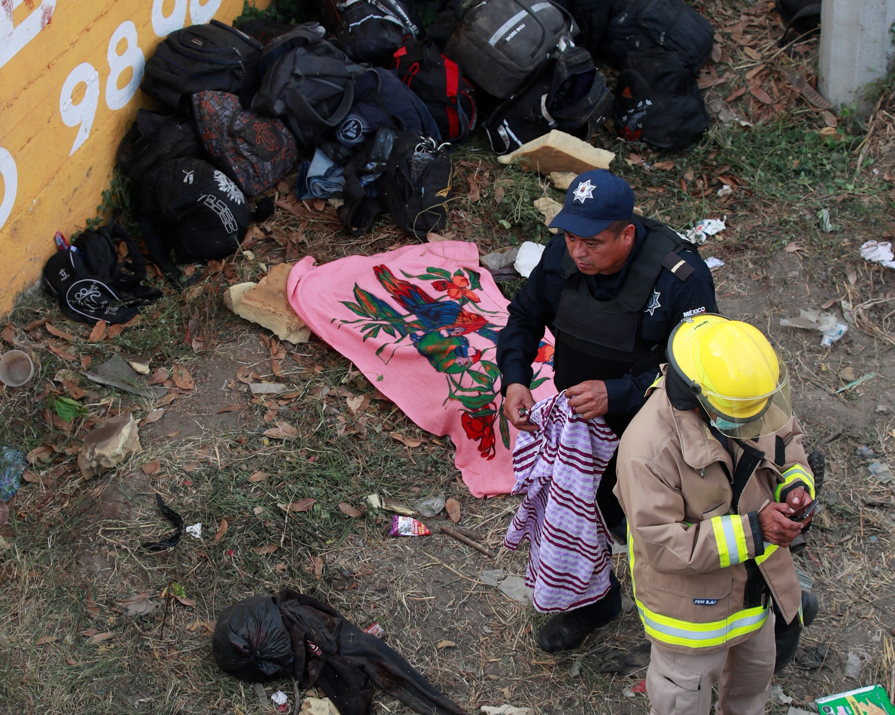 Two rescue workers near dozens of backpacks.