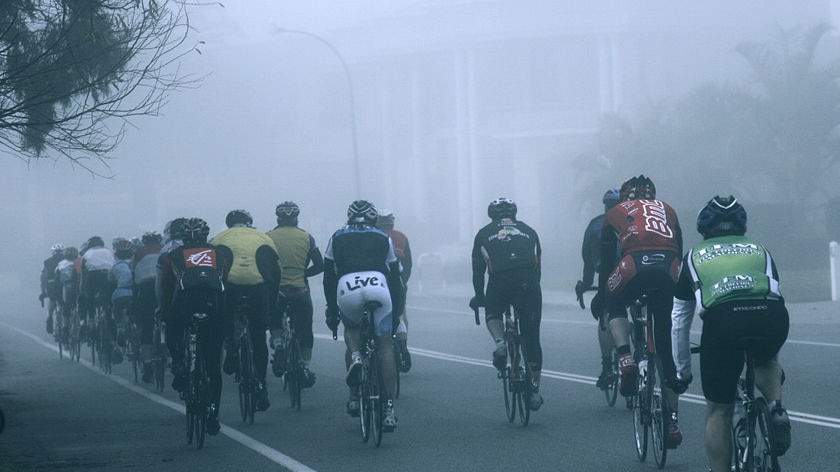 Cyclists ride through early-morning fog in Perth