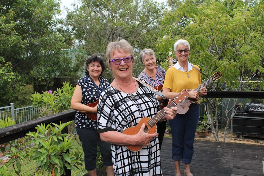 Four women with ukulele's stand outside