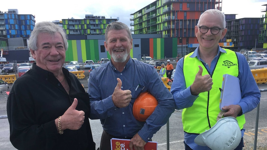 Three subcontractors give the thumbs up outside the Gold Coast Commonwealth Games village.