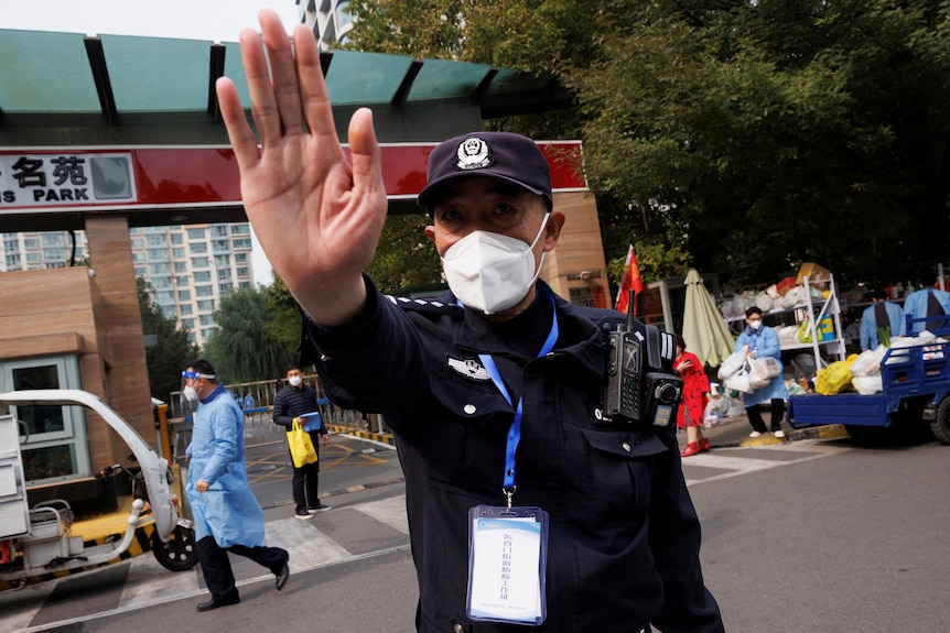 A police trying to stop photographers from entering a living compound