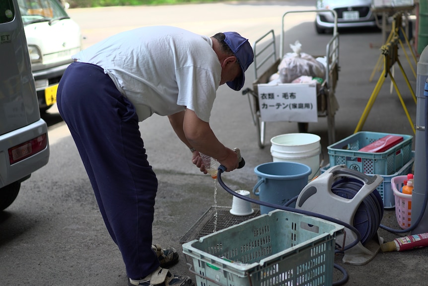 Kamikatsu resident hoses a bottle at the local recycling centre.