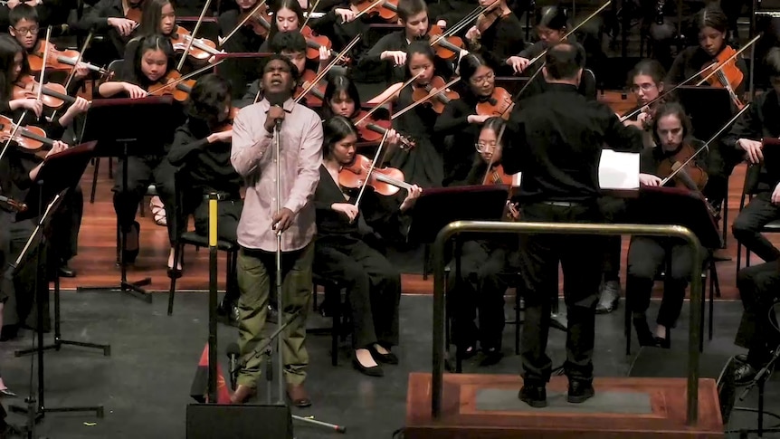 A man sings in front of an orchestra.