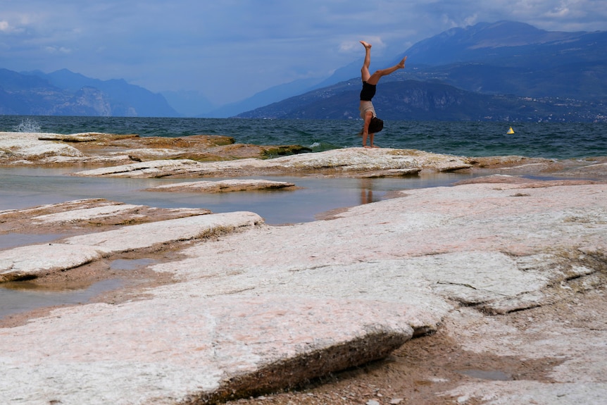 A woman plays at rocks on Lake Garda