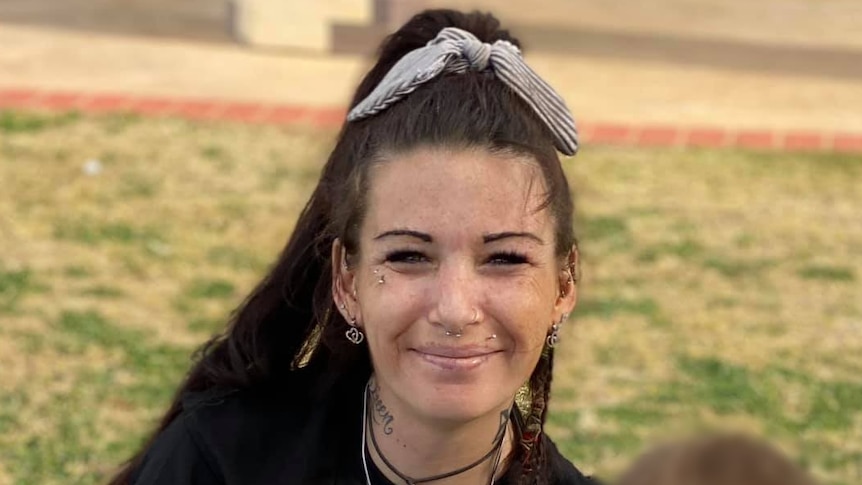 Woman smiles at the camera will sitting on grass