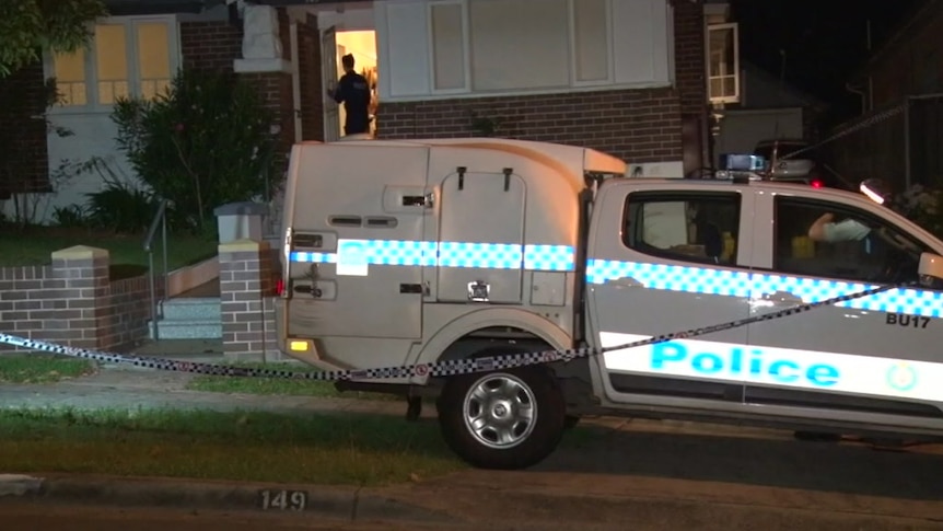 A police car is parked outside a home which is surrounded by police tape.